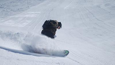 Snow boarder boarding along ski fields