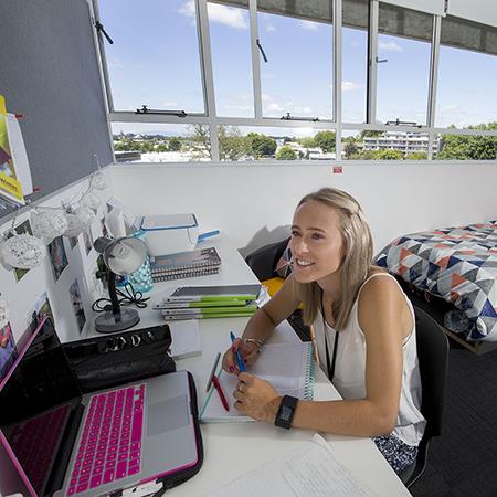 Woman seated at desk using laptop in Student Apartment bedroom