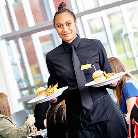 Student waiter carrying food to table