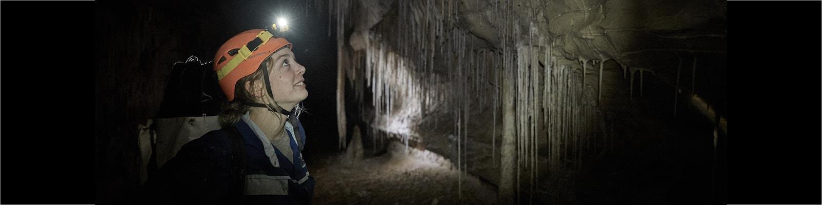 Student standing in cave wearing headlamp